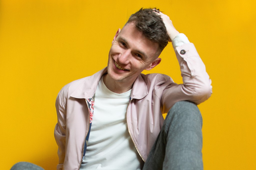 Joe Garvey smiling against a yellow backdrop